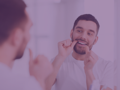 Image of a man flossing his teeth facing a mirror representing preventive dental care